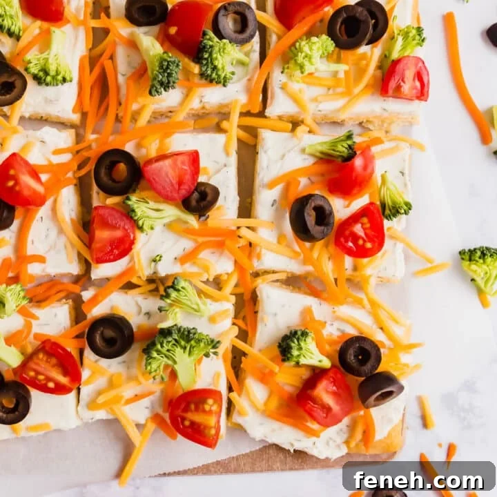 Crescent roll pizza slices lined up on a cutting board with veggies around it.