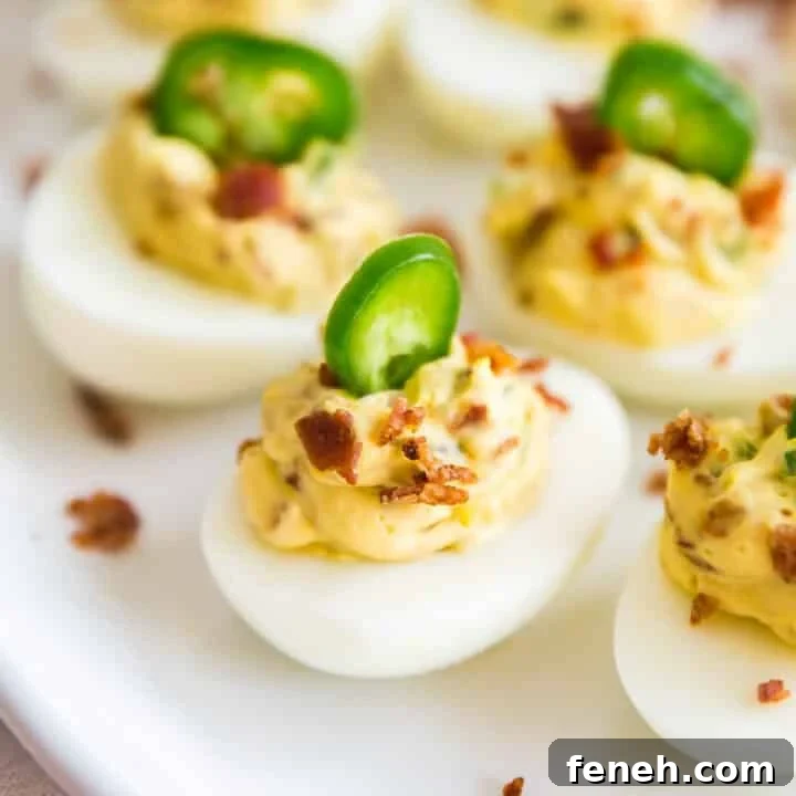 A close up of a jalapeno deviled egg on a plate with others.