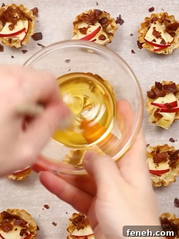 A hand drizzling honey over the baked phyllo cups.