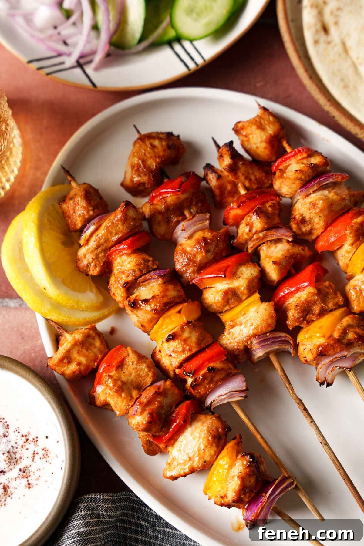 air fryer chicken kebabs on a plate with lemon slices on a brown background.