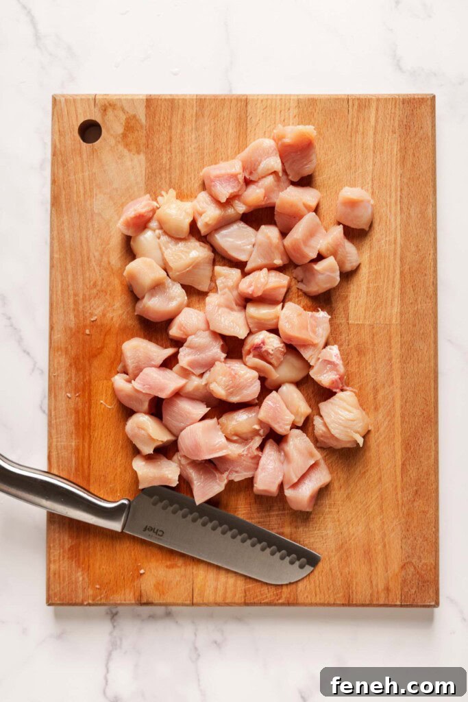 chicken cut into cubes for skewers on a chopping board.
