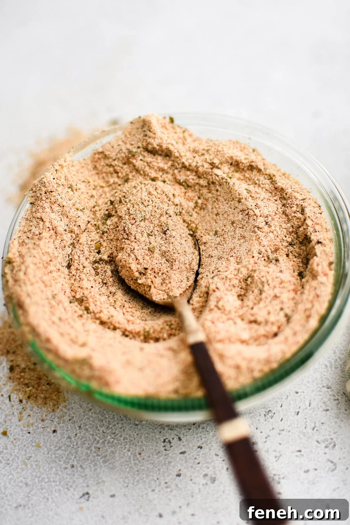 Glass jar filled with homemade Shake and Bake seasoning with a spoon set on top.