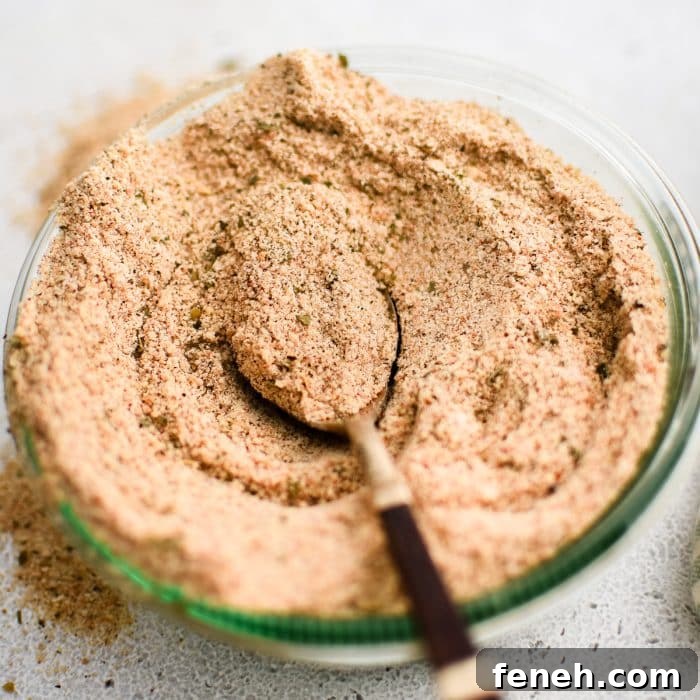 Glass jar filled with homemade Shake and Bake seasoning with a spoon set on top.