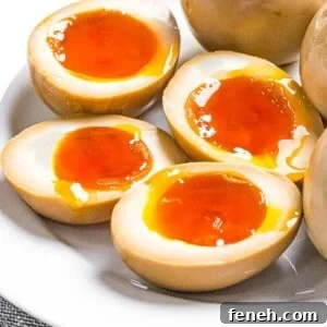 Ramen eggs marinated in soy sauce cut in half to reveal soft boiled eggs with runny yolks.