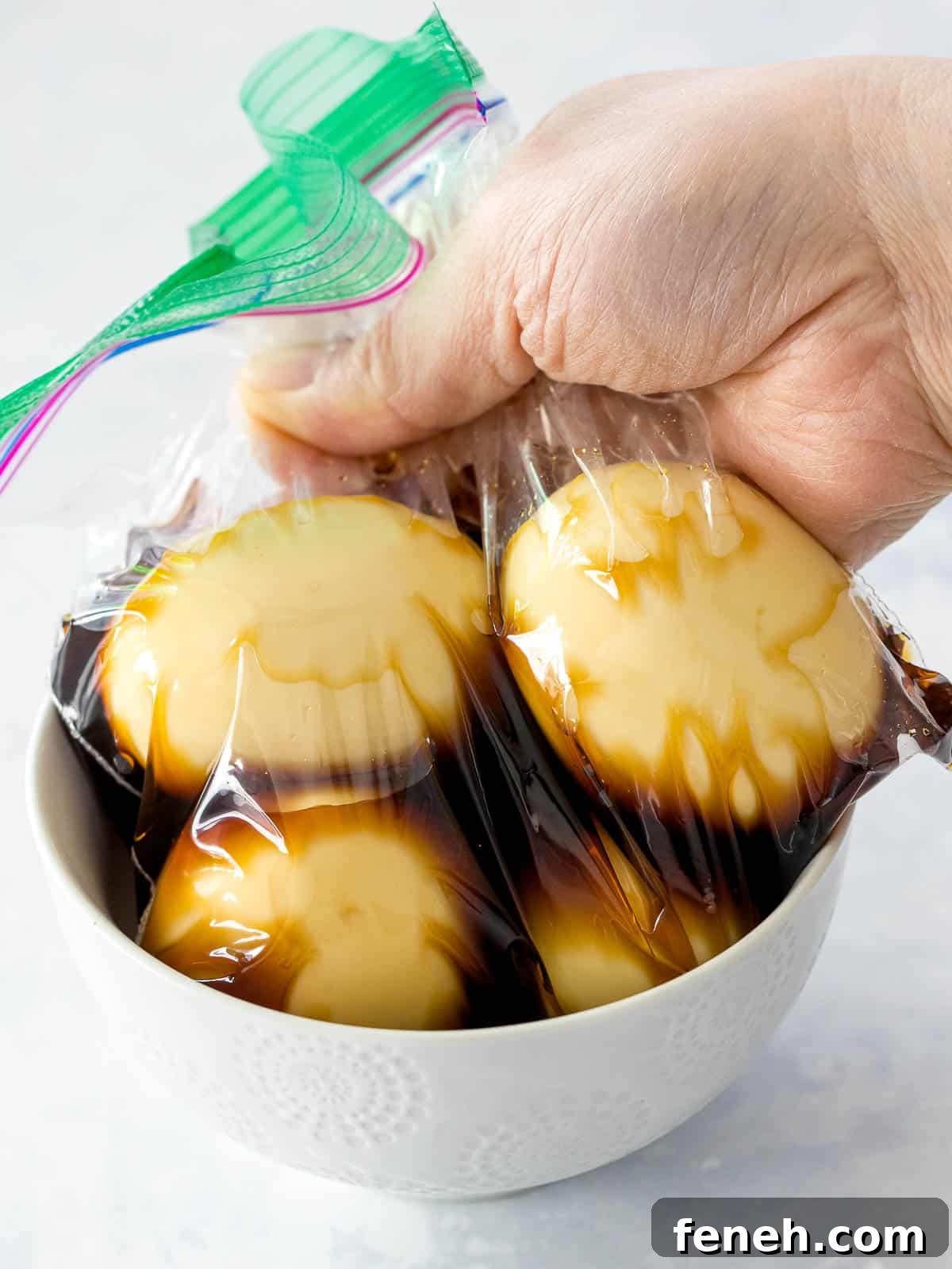 Soy sauce eggs marinating in soy sauce and mirin inside a plastic bag place in a bowl.
