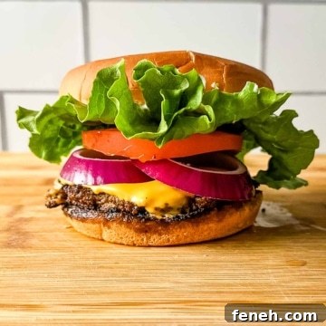 A turkey smash burger on a wooden cutting board in front of subway tile.