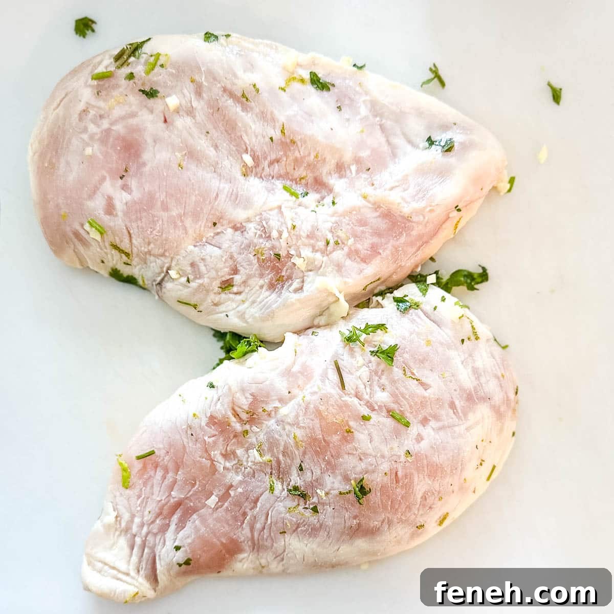 Raw marinated chicken on a white cutting board.