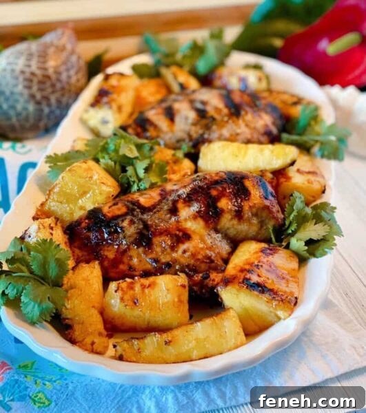 Platter filled with grilled jerk chicken breasts, grilled pineapple spears, and cilantro.