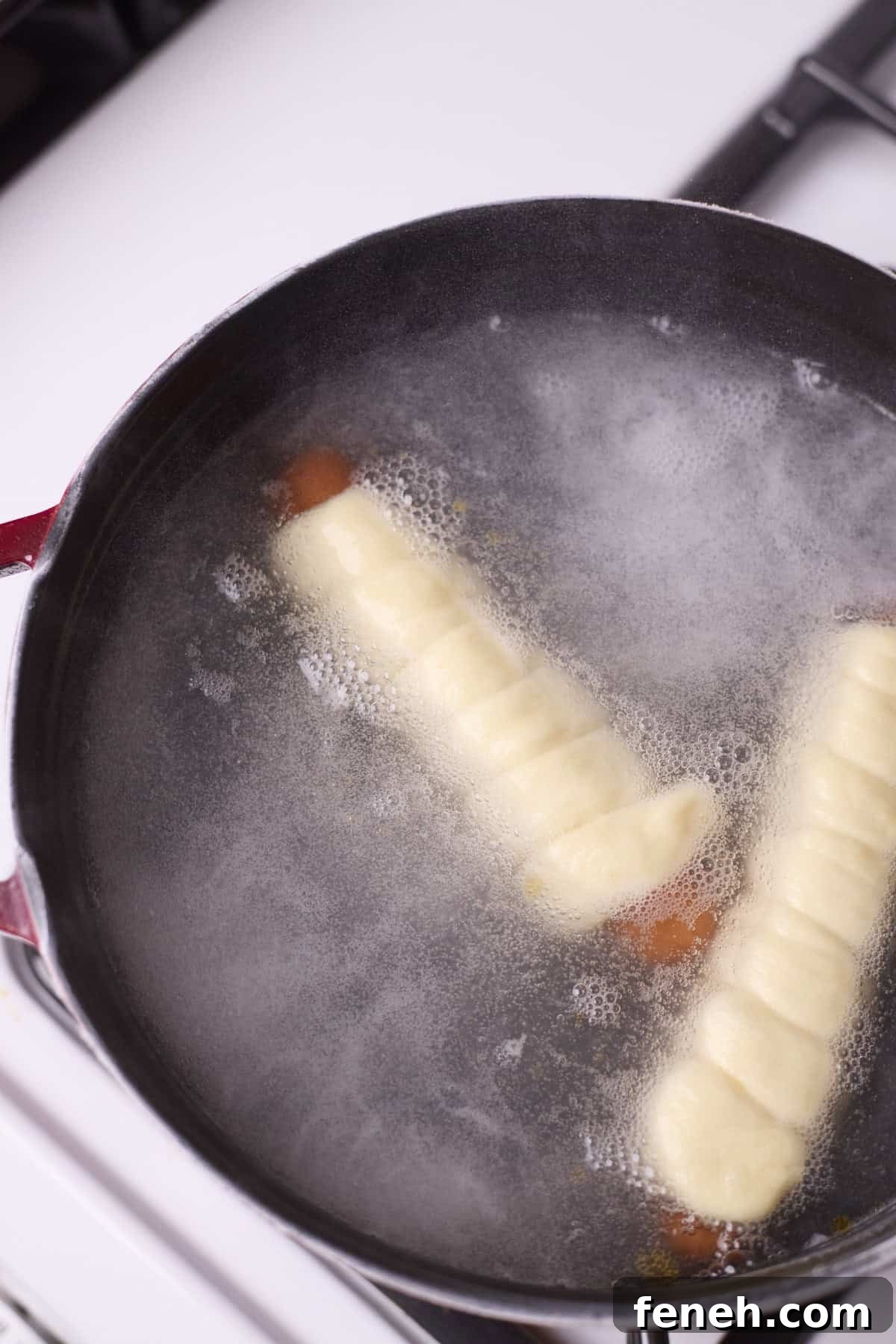 Pretzel-wrapped hot dogs floating in boiling water.