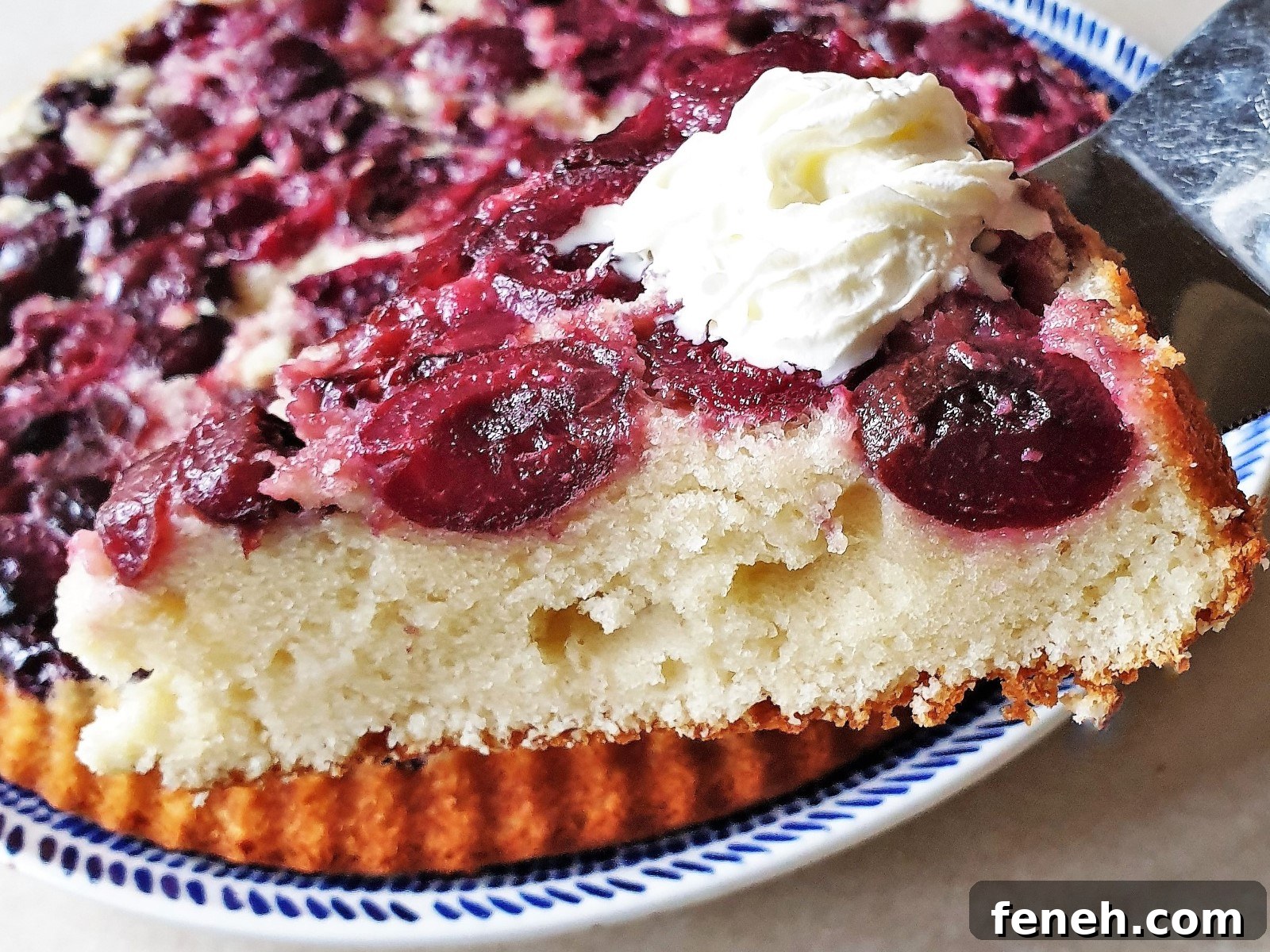 A slice of upside down cherry cake topped with whipped cream.