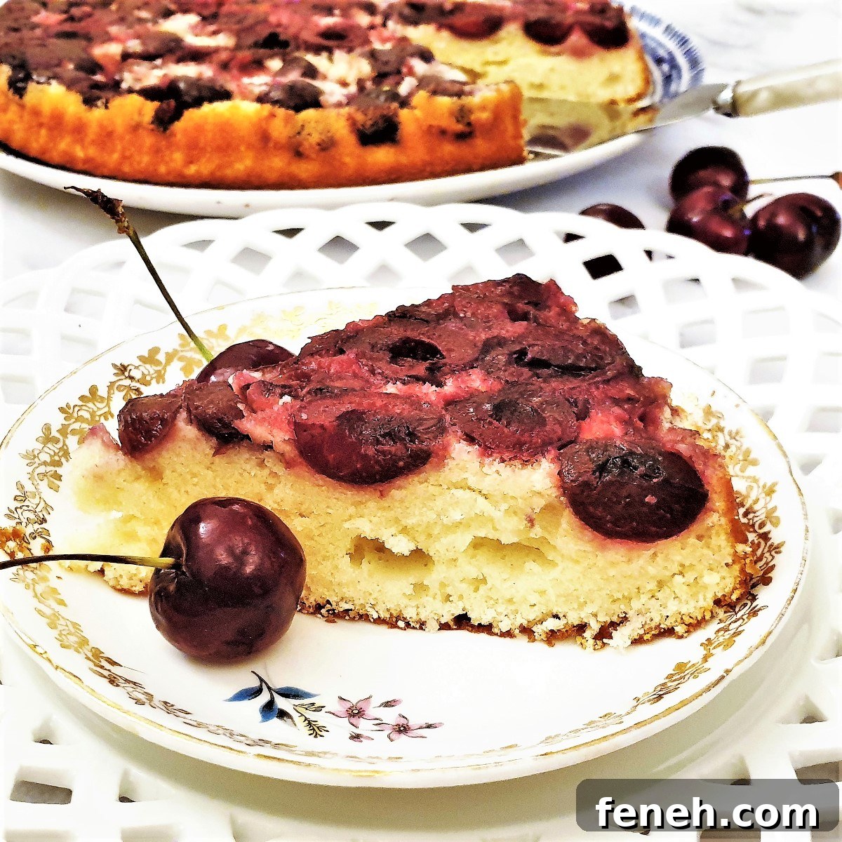 A slice of upside down cherry cake next to fresh cherries.