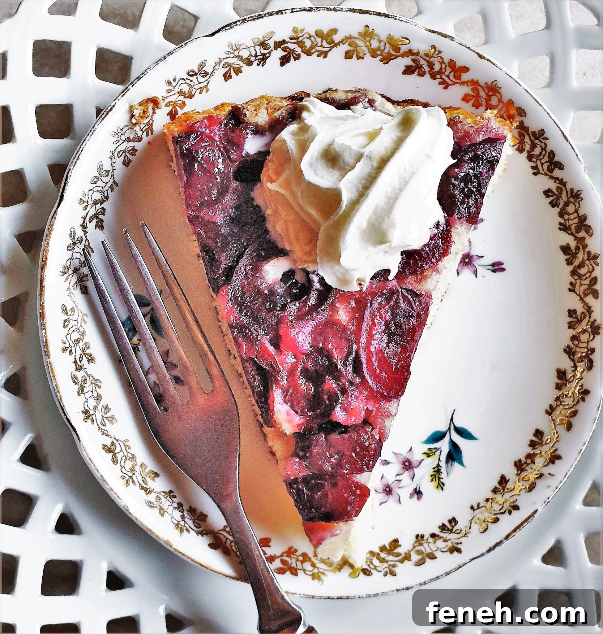 A slice of cherry cake on a plate, topped with whipped cream.