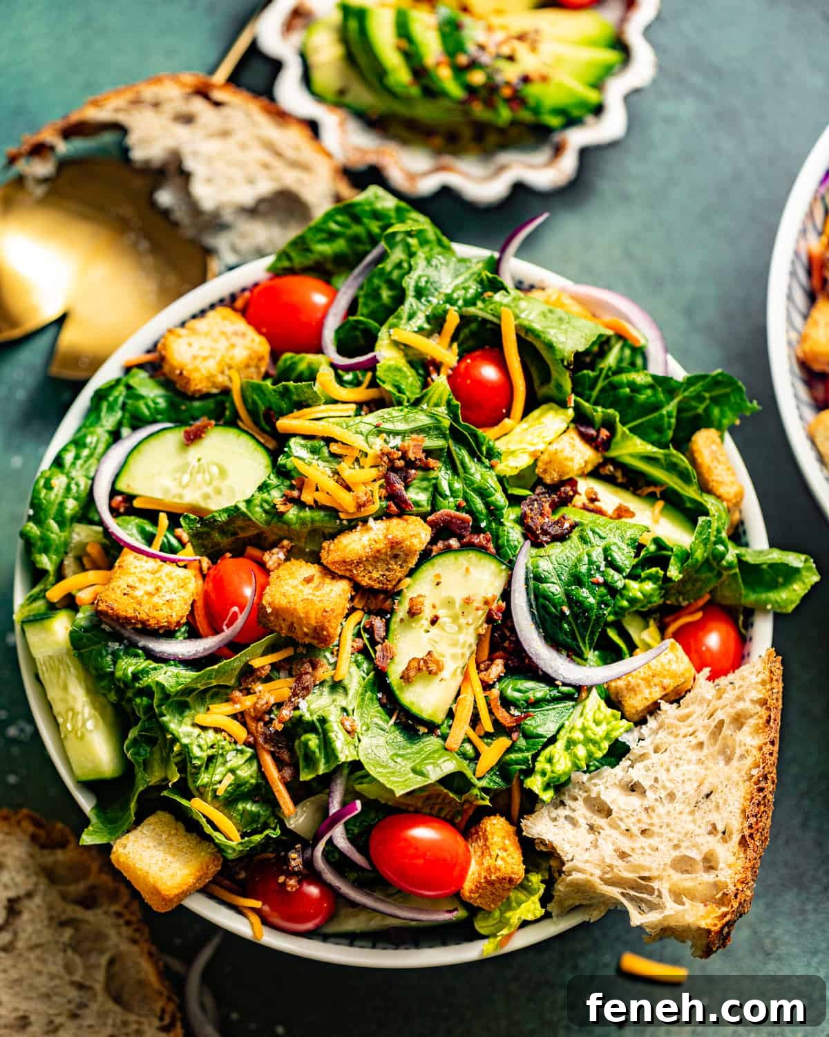 house salad in a large bowl with bread and a salad tosser.