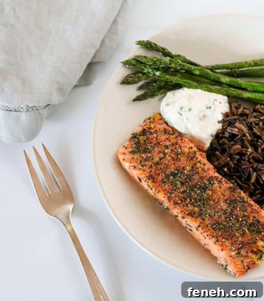Grilled salmon, asparagus, wild rice and creamy sauce on a plate with a fork and napkin