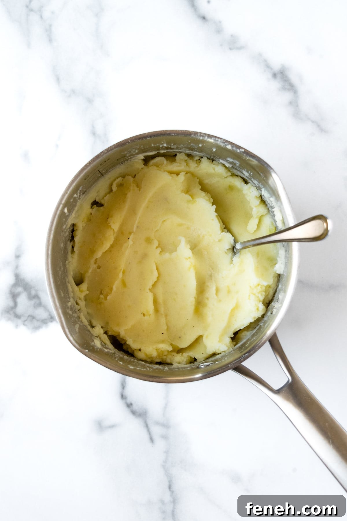 Mashed Potatoes in a pot with a spoon.