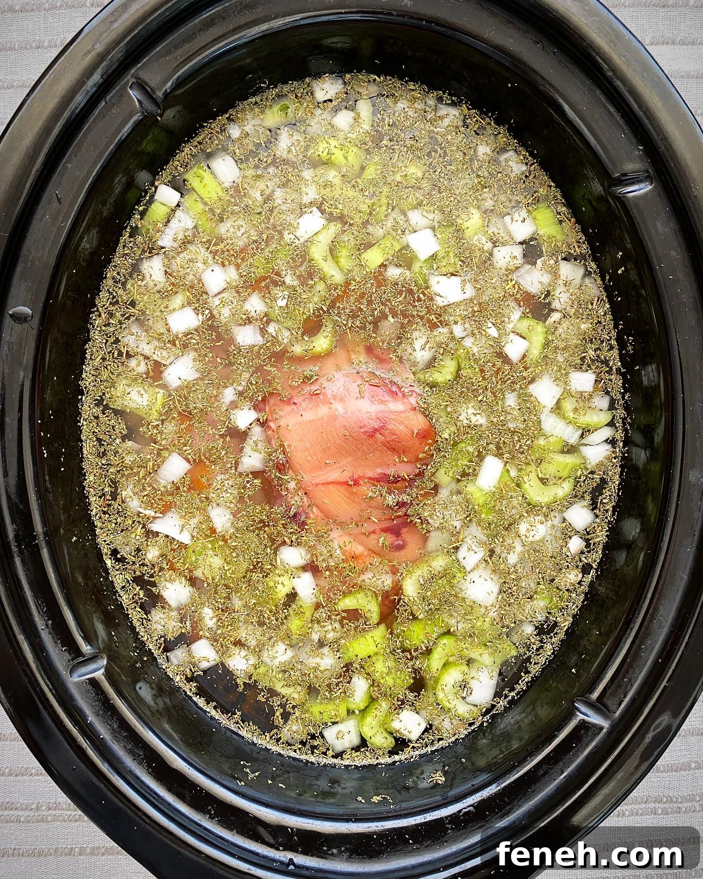 overhead shot of uncooked crockpot ham and bean soup in a black slow cooker