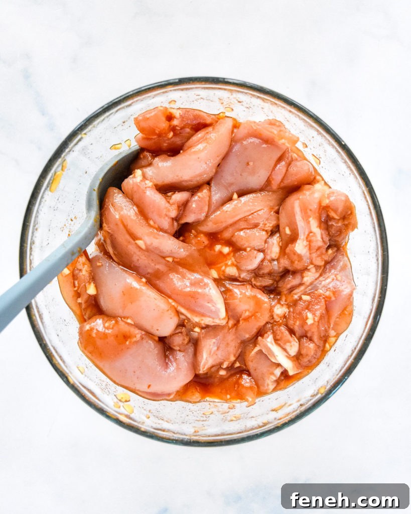 honey sriracha chicken marinating in a glass bowl.