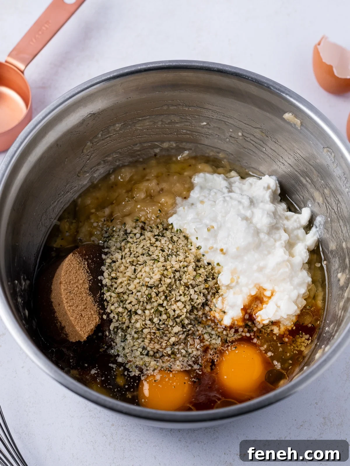 stainless steel bowl with the wet ingredients- mashed banana, brown sugar, cottage cheese, eggs, vanilla, hemp hearts