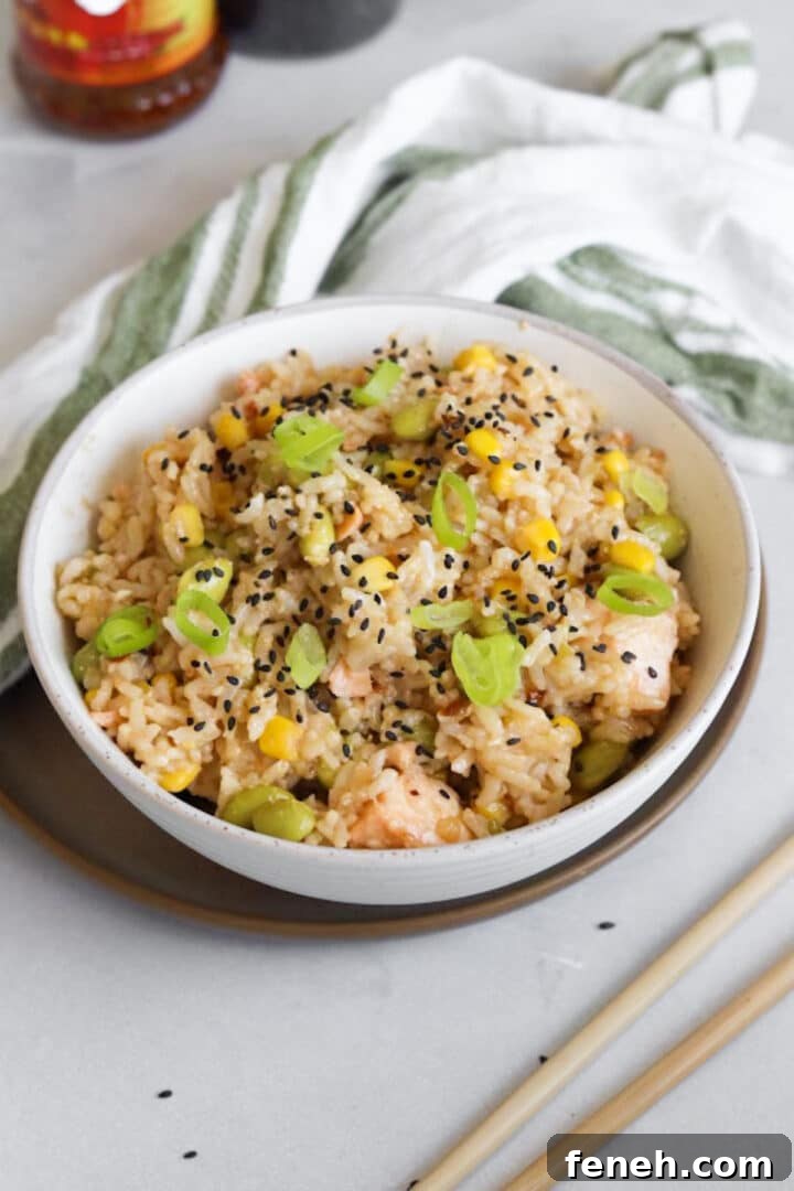 One pot salmon rice bowl made in the rice cooker plated in a white bowl and topped with sesame seeds