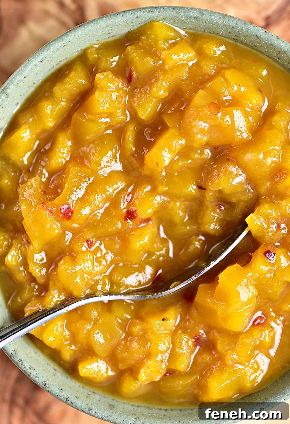 Close up image of mango chutney in a green bowl. Silver spoon.