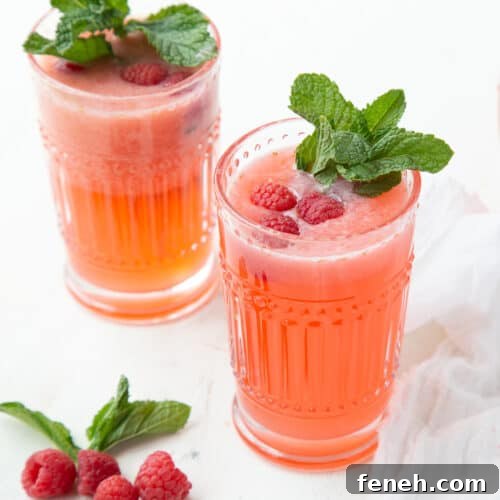 two glasses of raspberry lemonade garnished with fresh mint.