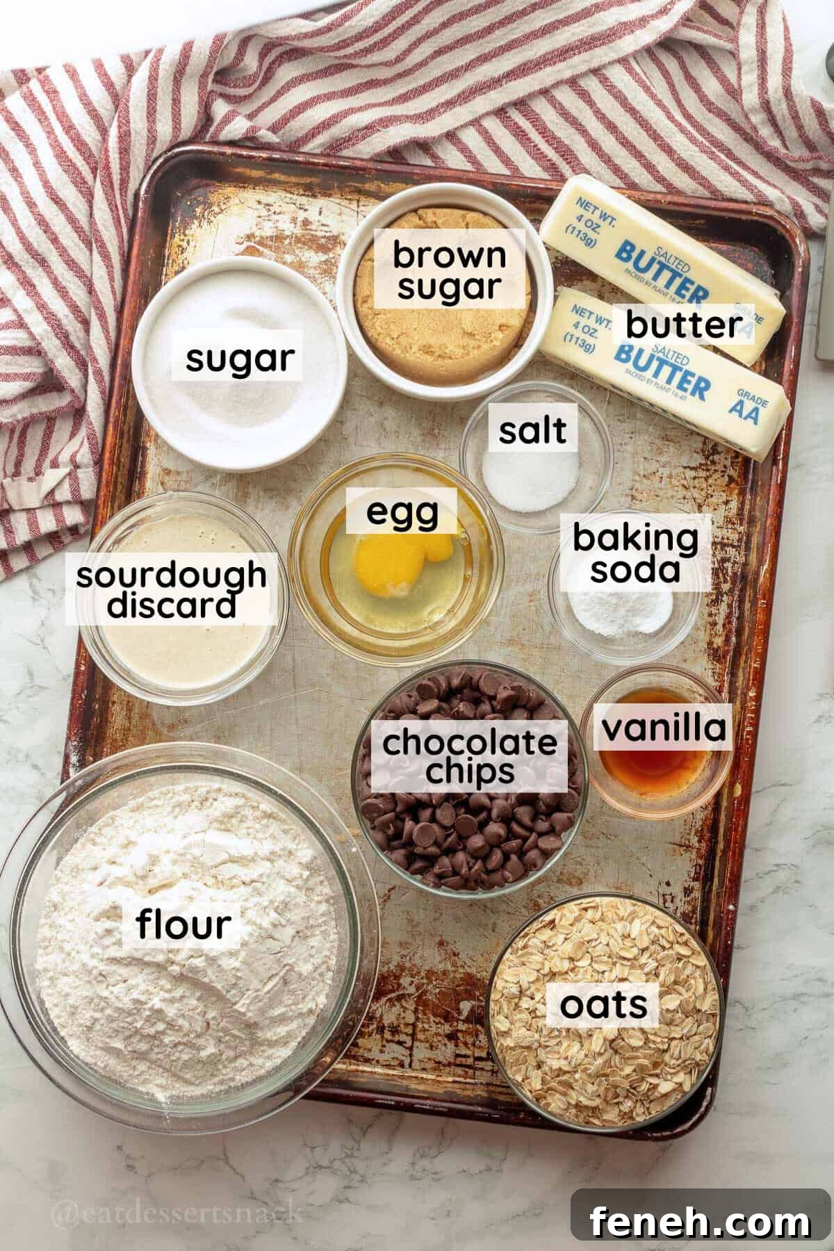 Labeled ingredients for sourdough oatmeal cookies on metal baking sheet.