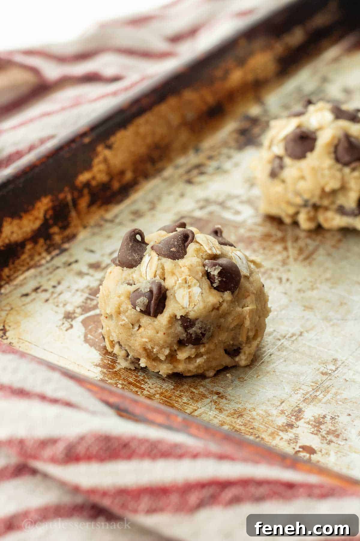 Raw cookie dough ball on metal baking sheet.